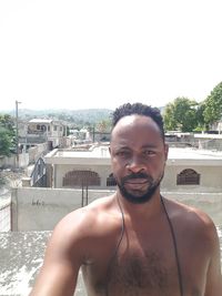 Portrait of young man standing in swimming pool against sky