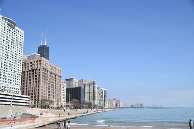 City at waterfront against blue sky