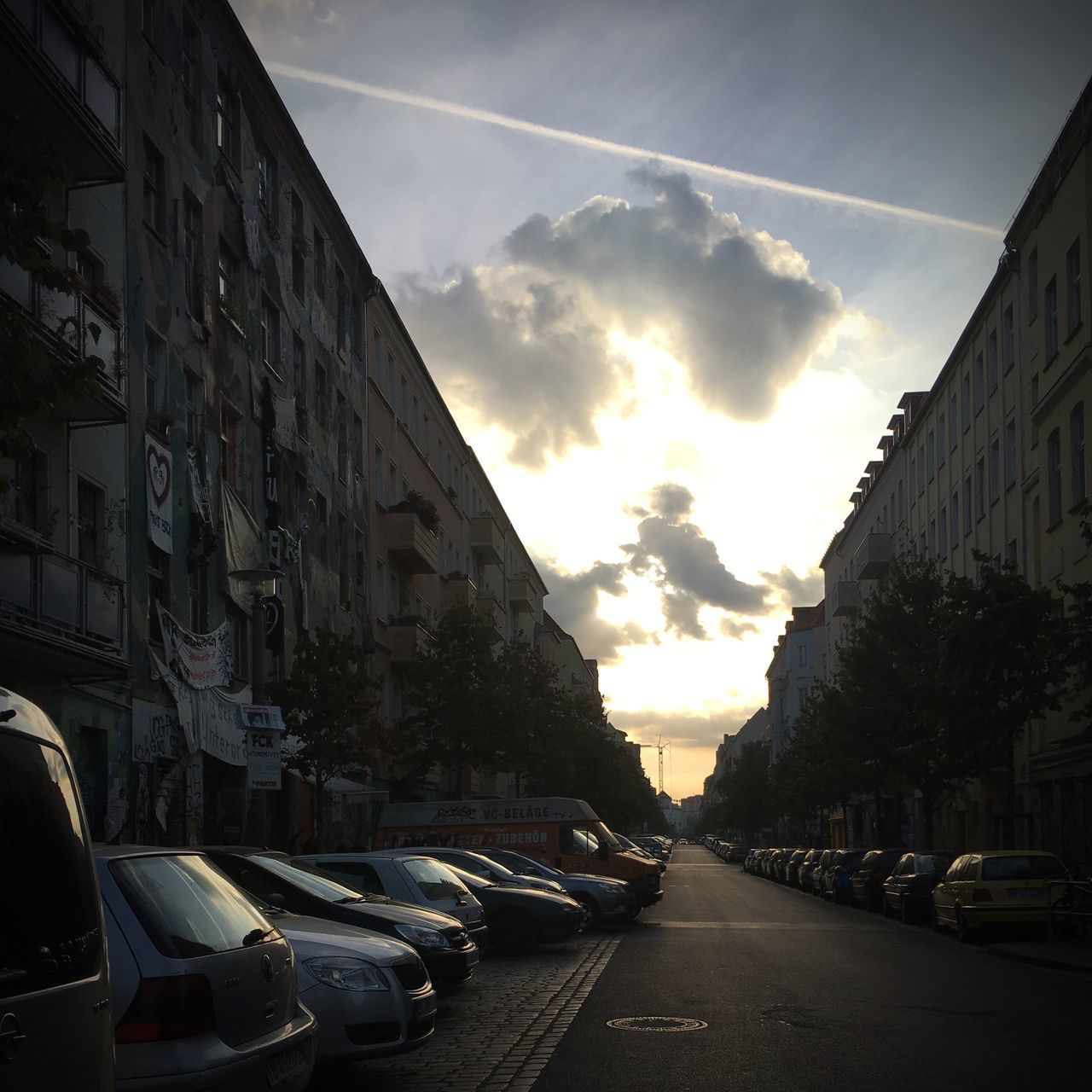 CARS ON ROAD AMIDST BUILDINGS AGAINST SKY