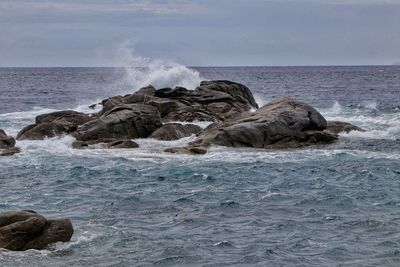 Scenic view of rocks in sea against sky