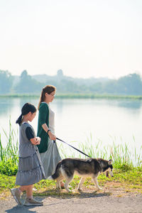 Woman with dog standing by lake