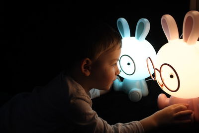 Close-up of hand holding toy against black background