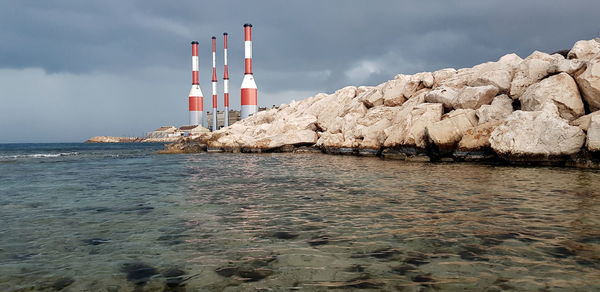 Lighthouse by sea against sky