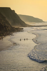 Group of surfers going to surf in the ocean at the sunset.