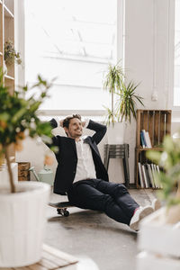 Smiling businessman sitting on skateboard