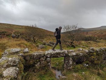 Man walking over land on rock