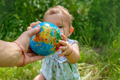 Hand of man giving globe to baby