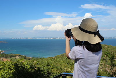 Rear view of woman photographing sea against sky