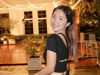 Portrait of young woman standing against house