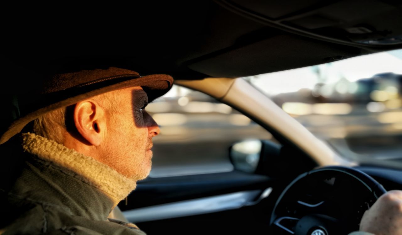 transportation, motor vehicle, car, mode of transportation, vehicle interior, one person, land vehicle, car interior, portrait, real people, driving, men, headshot, adult, steering wheel, lifestyles, looking, clothing, focus on foreground, mature men, outdoors, road trip, warm clothing
