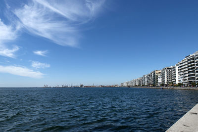 View of city at waterfront against blue sky