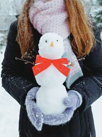 Midsection of woman holding snowman at yard