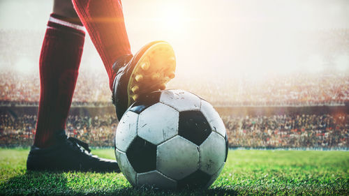 Feet of red team soccer player tread on soccer ball for kick-off in the stadium