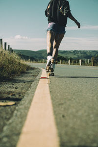 Surface level view of woman roller skating on road against sky