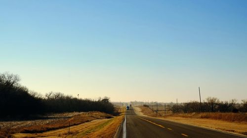 Road amidst trees against clear sky