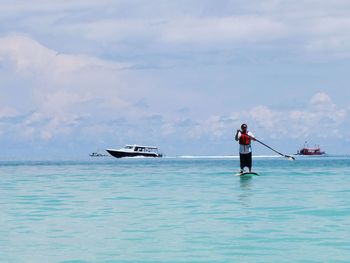 Full length of woman paddle boarding on sea against sky