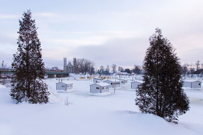 Atlantic tomcod ice fishing cabins on a frozen river with a bridge and church in the background