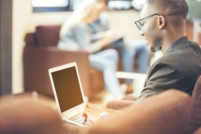 A black man works on a tablet computer in the hotel lobby.