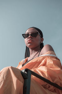 Low angle view of man wearing sunglasses standing against sky