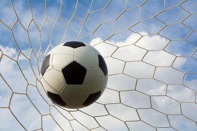 Low angle view of soccer ball in net against sky