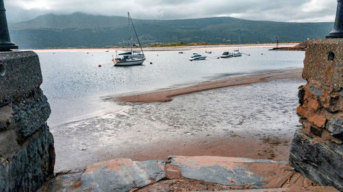 Sailboats on sea shore against sky