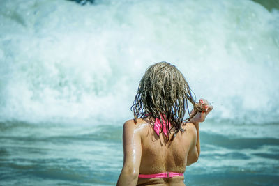 Rear view of shirtless boy in sea