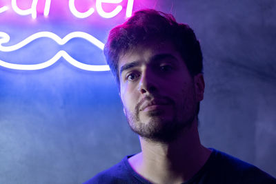 Portrait of handsome young man posing against neon lights