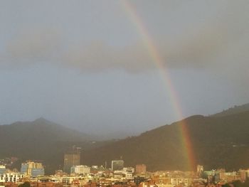 Rainbow over city against sky