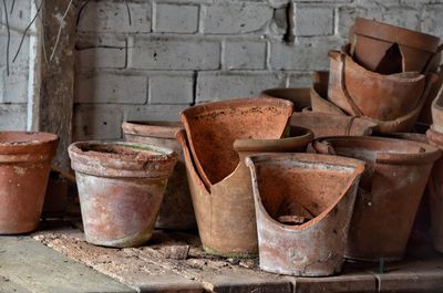 Broken flower pots on wooden table against brick wall