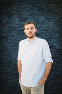 Portrait of young man standing against wall