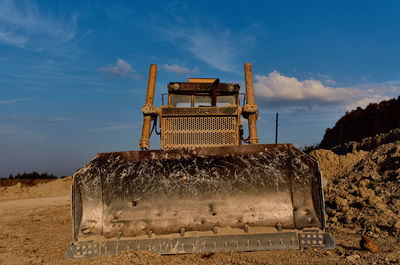 Old metal structure on field against sky