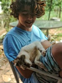 Smiling boy with cat sitting on chair