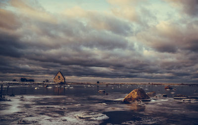 Frozen lake against cloudy sky