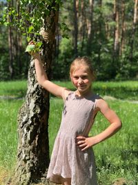 Portrait of happy girl standing by tree in forest