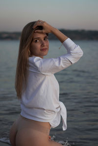 Beautiful woman sitting at beach against sky