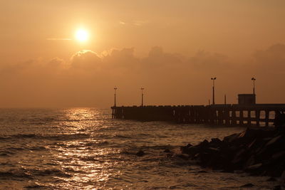 Silhouette pier over sea against sky during sunset