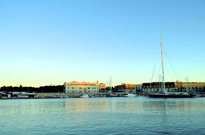 Sailboats moored in harbor against clear blue sky