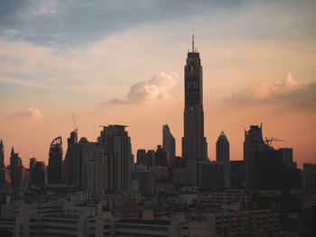 Modern buildings in city against sky during sunset