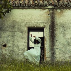 Young woman with umbrella standing in front of house