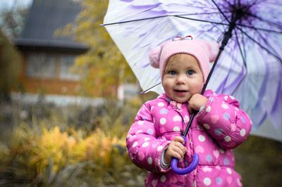 Portrait of cute girl holding umbrella during rainy season