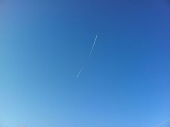 Low angle view of vapor trail against clear blue sky