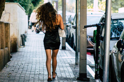 Rear view of woman walking on footpath in city