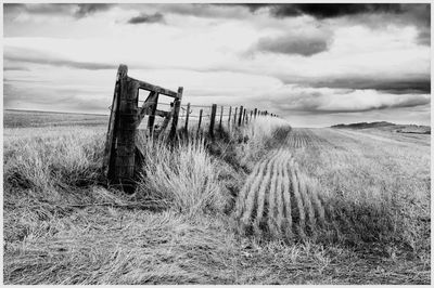 Wooden fence on field against sky