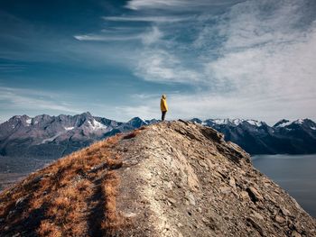 Man standing on rock by snowcapped mountain against sky