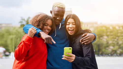 Smiling friends taking selfie while standing outdoors