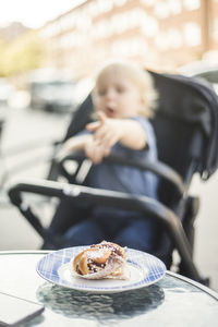 Fresh pastry served in plate with baby boy on stroller at sidewalk cafe