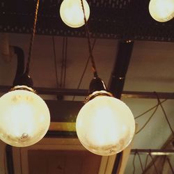 Low angle view of lit lamp hanging on ceiling