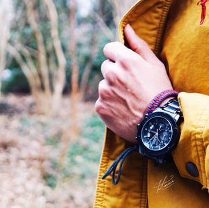 Close-up of hand holding clock against blurred background