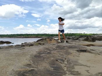 Full length of boy standing on beach against sky