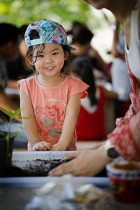 Portrait of smiling cute girl standing by woman gardening 